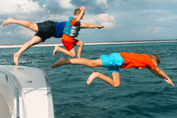Photo of 3 boys diving off side of Pontoon Boat and into the sea