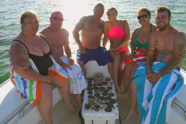 Photo of a group that rented a Pontoon boat and went to Shell Island. They are at the end of the boat and around the shells they collected from their trip