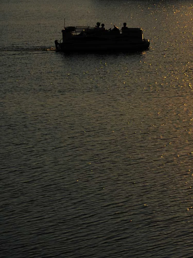 Pontoon boat on the water at sunset