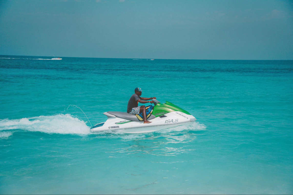 Image of a man riding a jetski in the shallow end of the ocean.