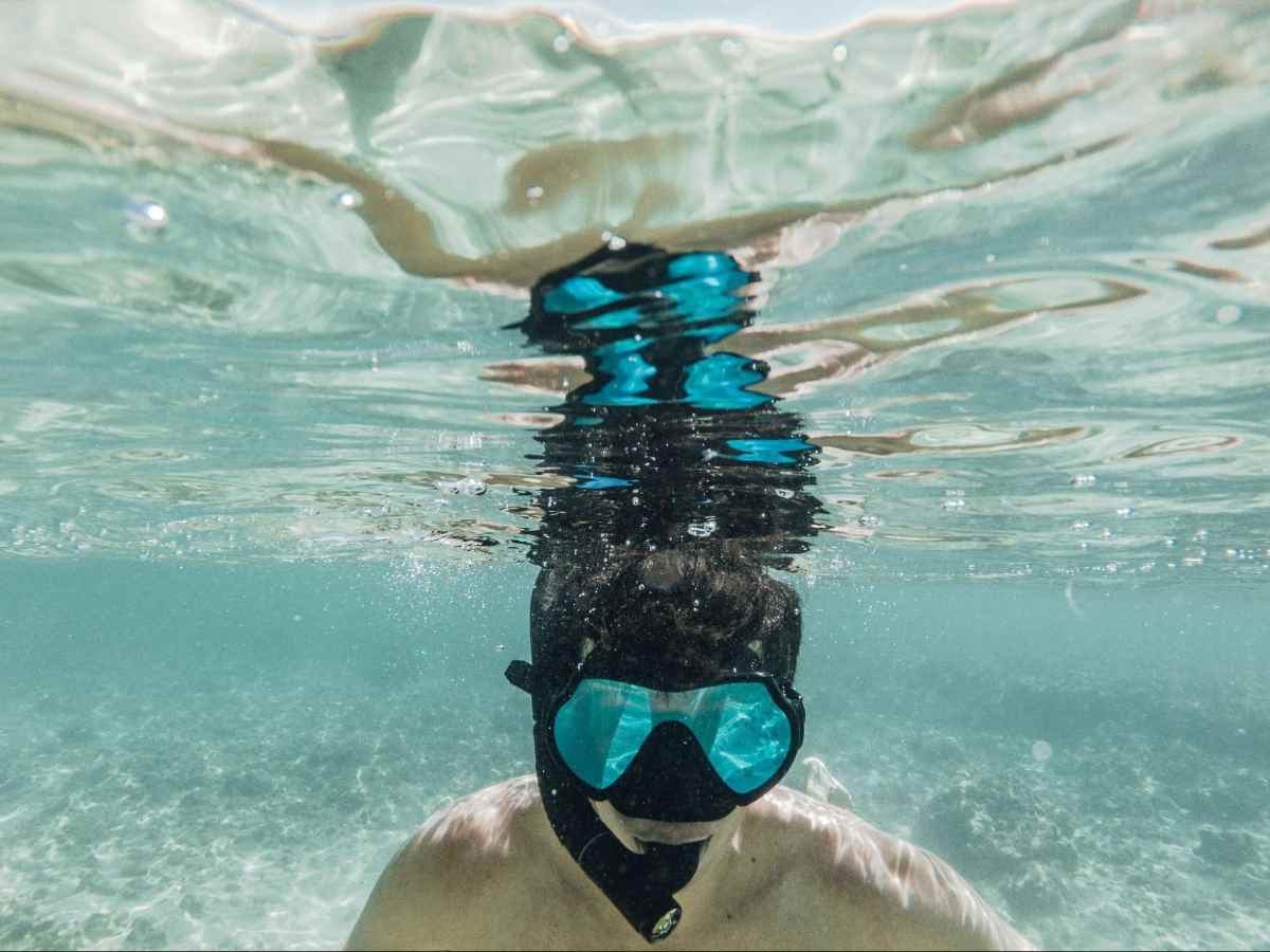 Image of teen boy with snorkeling gear in shallow tropical water.